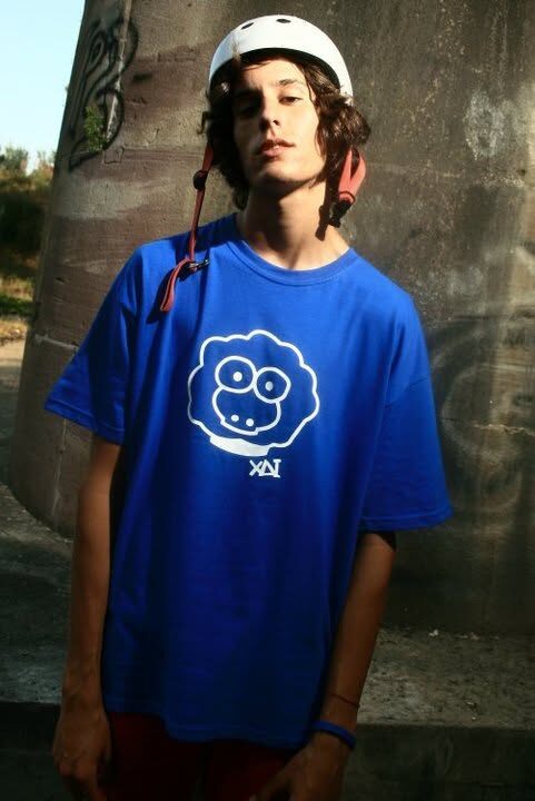 A young rider in a blue XAI t-shirt with the sheep logo, wearing a white helmet