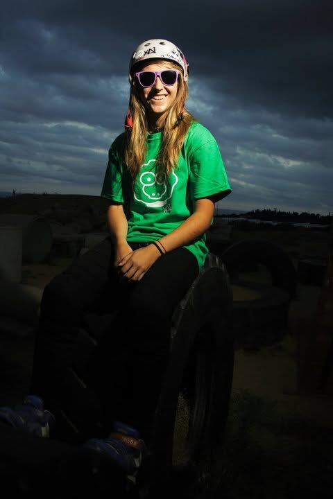 A girl in a green XAI t-shirt sitting on tyres under a dramatic sky