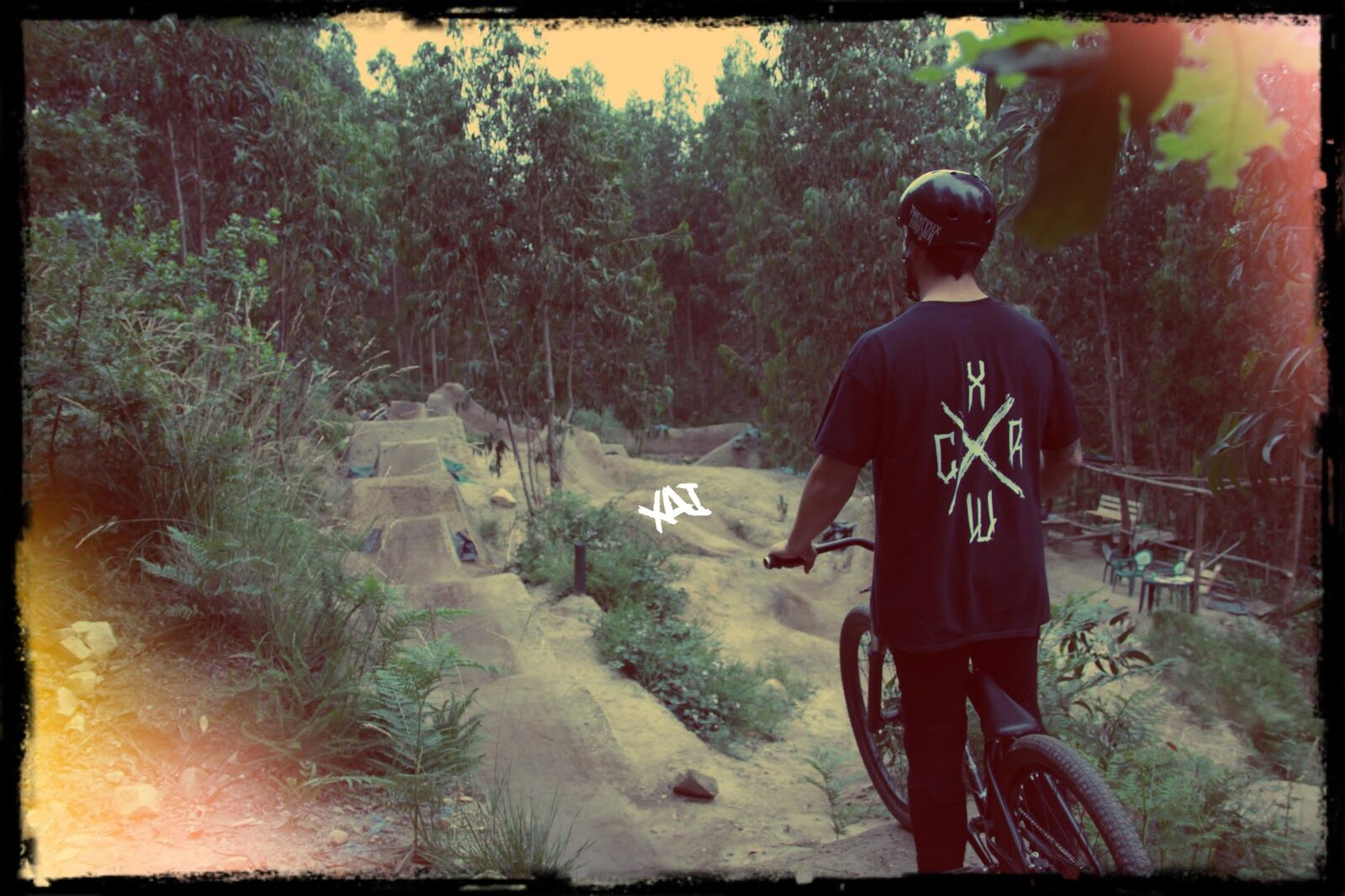 A rider looking down a line of dirt jumps, faded film treatment