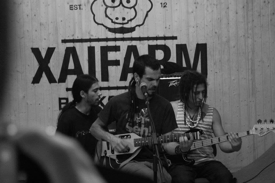 Black and white photo of a band playing live inside the XAI FARM shop, under the shop's sheep logo and wordmark