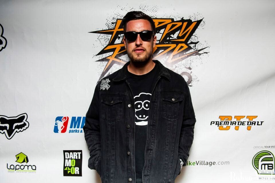 A rider in a denim jacket in front of the sponsor backdrop