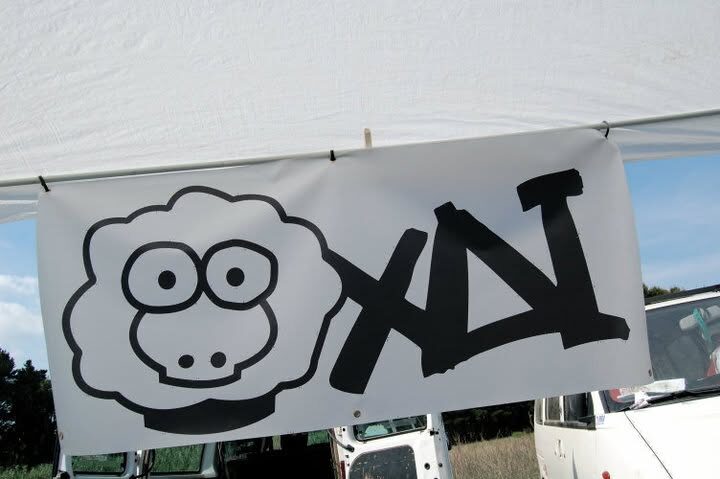 A large printed XAI banner with the sheep and wordmark, strung up at an outdoor event
