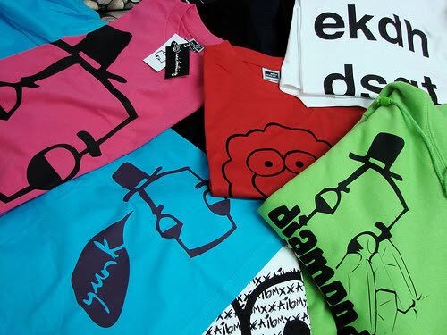Flat lay of brightly coloured t-shirts with spray can and sheep graphics