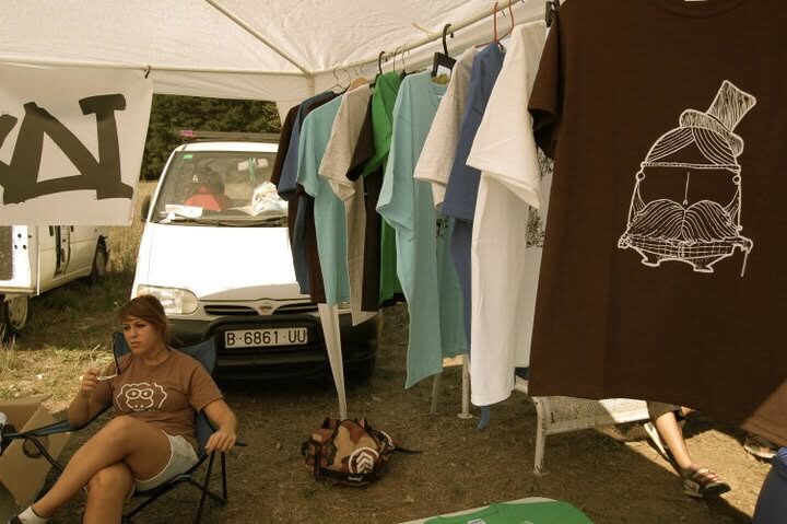A XAI stall at an outdoor event, shirts hanging from a rail beside a van