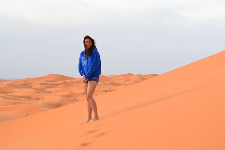 A person in a blue XAI hoodie standing alone on a desert dune