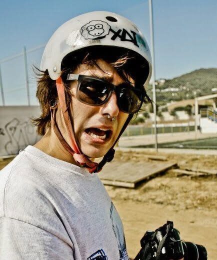 A rider wearing a white helmet with the XAI sheep and wordmark stickered on it