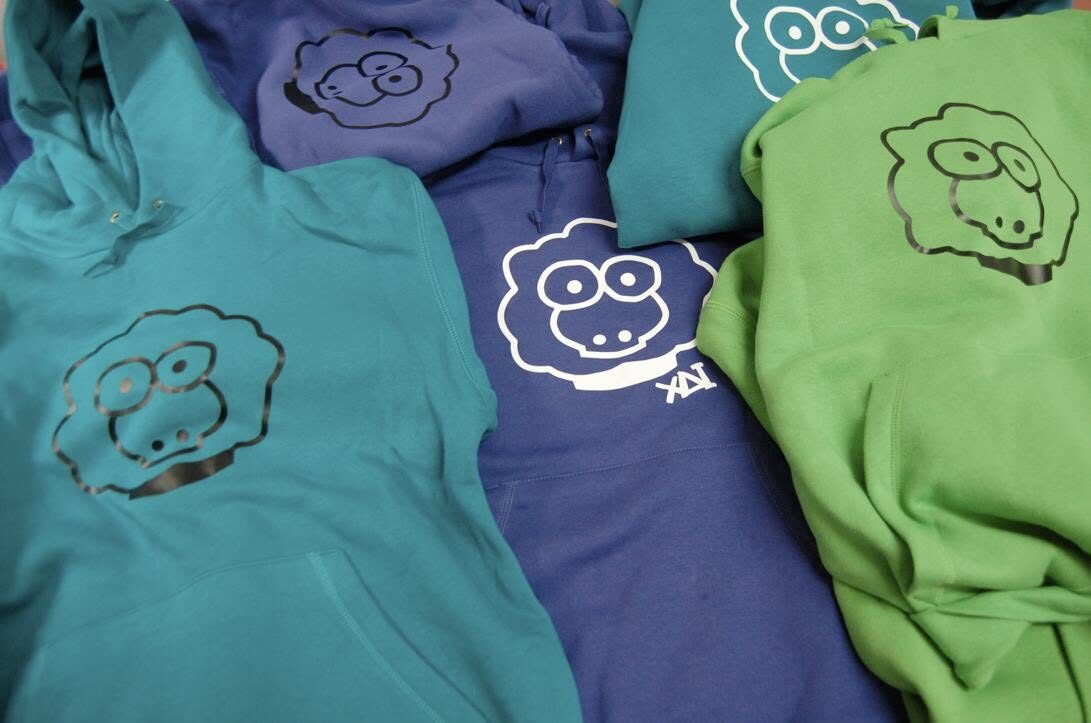 Folded hoodies in teal, blue and green with sheep prints