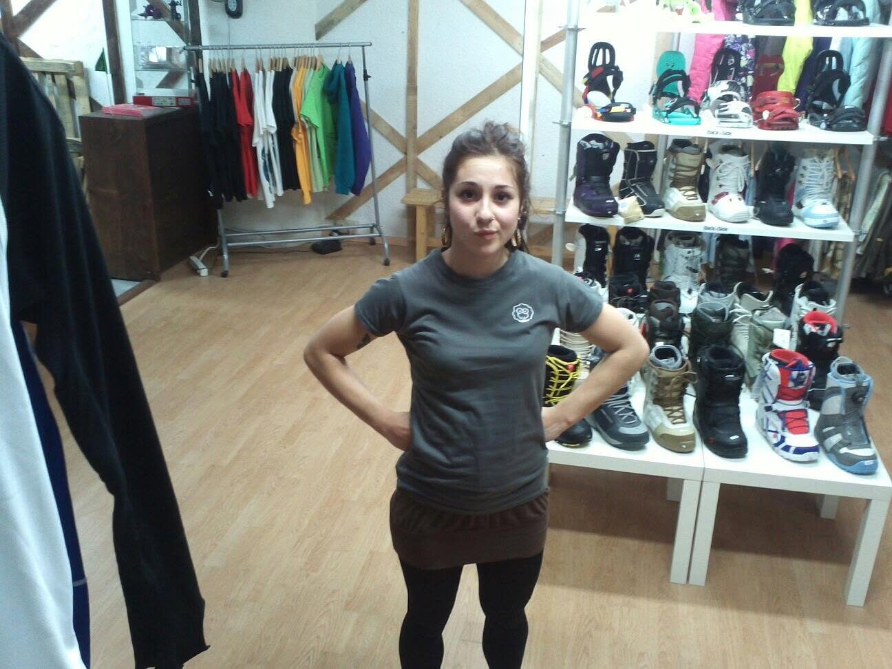 A girl wearing a XAI shirt in a shop, sneakers displayed behind her