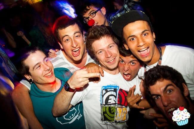 A crowd of friends piled together at a party, several in XAI shirts