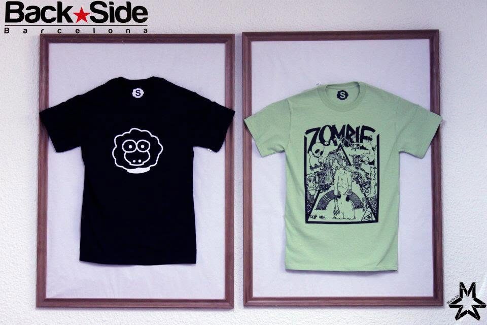 Two XAI t-shirts framed and displayed on a wall under a Back Side sign